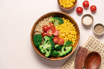 Broccoli, corn, quinoa, tomato salad in wooden bowl on light beige background. Healthy food concept