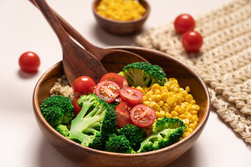 Broccoli, corn, quinoa, tomato salad in wooden bowl on light beige background. Healthy food concept