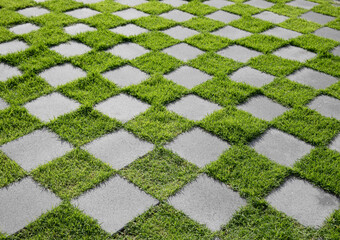 Checkered pattern of green grass and cement tiled floor