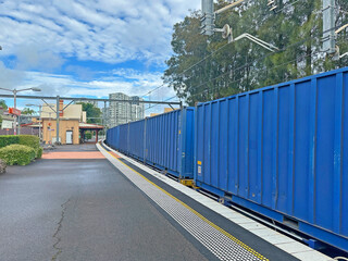 Long blue freight train going past a city train station