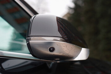 Car side mirror with integrated camera closeup, cam for driver safety and visibility. Car side view camera system integrated into rearview mirror, blind spot detection, 360 visibility.