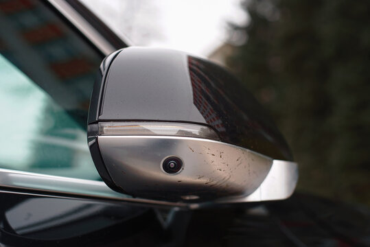 Fototapeta Car side mirror with integrated camera closeup, cam for driver safety and visibility. Car side view camera system integrated into rearview mirror, blind spot detection, 360 visibility.