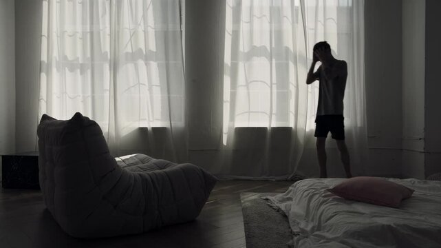 Man walking nervously back and forth in dark room, struggling with anxiety and mental overload.