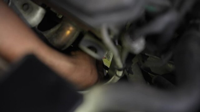 A man is rubbing the chassis number area under the hood of a car to make a chassis number impression for verification or registration purposes. Gesek no rangka