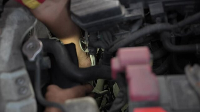 CLOSE UP OF MECHANIC'S HANDS CHECKING THE MACHINE AND INSERTING HAND INTO THE GAPS OF THE MACHINE.