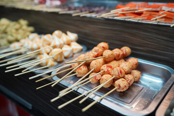 A variety of skewered fish balls and seafood on a tray displayed at a street food stall in Malang, Indonesia
