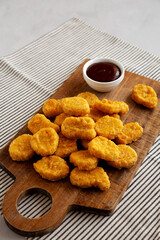 Organic Fried Chicken Nuggets on a wooden board, side view. Copy space.
