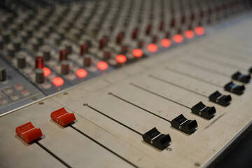 Close-up of a professional audio mixing console with red and black faders. Perfect for themes of...