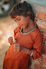 Candid image of an Indian girl in rural setting, deeply engaged in thought, great for storytelling...
