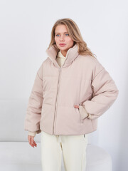 Studio fashion shoot featuring a young blonde model in a stylish beige puffer jacket © Dmitry Tsvetkov