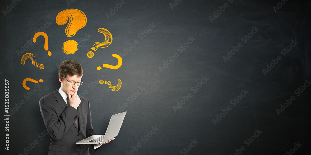 Poster businessman thinking while holding laptop with yellow question marks on dark chalkboard background, 