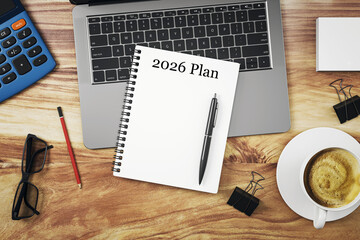 Top view of office desk with laptop, coffee cup, notebook titled 2026 Plan, pen, pencil, glasses,...