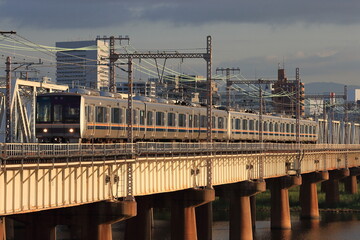 Naklejka premium 朝日に照らされながら淀川を渡るJR西日本321系電車_2010/8/26撮影