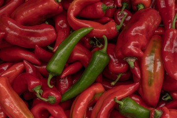 Ripe fresh peppers piled on farmer's market stall - bright spicy vegetable background.
