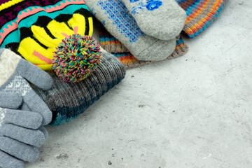 Warm clothes in the form of hats, mittens and scarves. There is space for text.