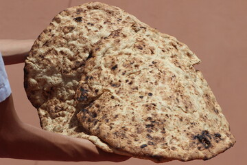 Hands holding a traditional moroccan bread known as tafarnout bread or tafournout bread