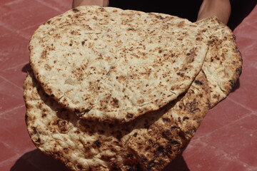 Hands holding a traditional moroccan bread known as tafarnout bread or tafournout bread