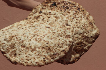 Hands holding a traditional moroccan bread known as tafarnout bread or tafournout bread