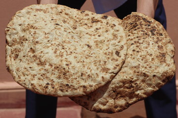 Hands holding a traditional moroccan bread known as tafarnout bread or tafournout bread
