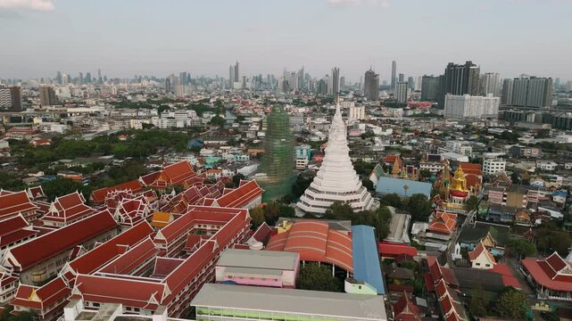 Aerial view of wat paknam phasi charoen temple with its iconic white chedi stands out against the backdrop of Bangkok sprawling urban landscape, Thailand.