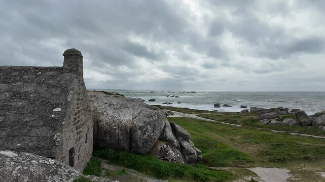 Stone House Between Granite Rocks in Meneham, Brittany, France with Ocean and Waves in the Background