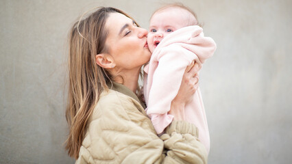 Close up portrait mother gently kissing her baby on the cheek