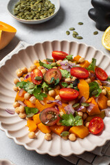 Fresh chickpea and pumpkin salad with tomatoes and herbs for healthy eating. Autumn salad