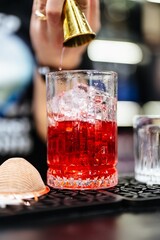 Crafting a vibrant cocktail with precision at a lively bar in the evening