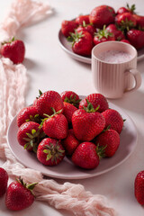 Fresh strawberries on pink plate with strawberry milkshake and fabric