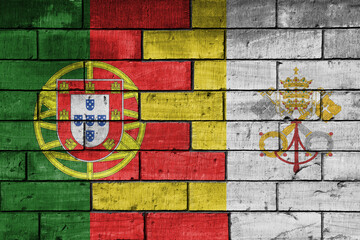 colourful painted big national flag of vatican city and flag of portugal on a massive old brick wall background. concept