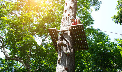 A man and a woman is walking across a challenging ropes course in the extreme park