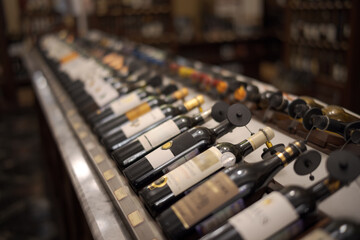Row of wine bottles with dry red and white wine on wooden. Low depth of field.