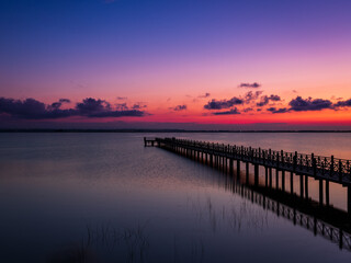Obraz premium Sunset over the pier and calm sea, peaceful landscape at dusk 