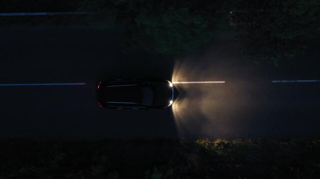 Aerial top down view of black car on the road at night