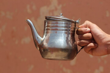 Hand holding an old metal teapot