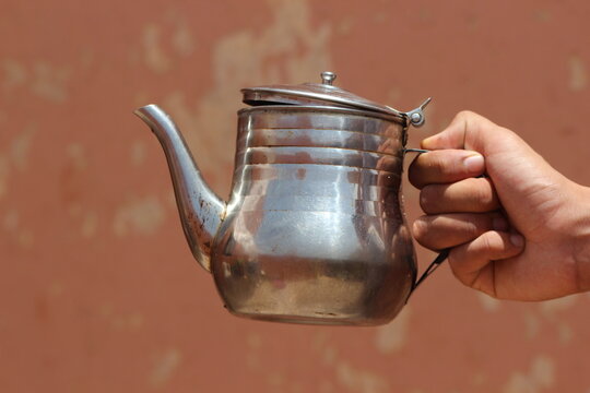 Hand holding an old metal teapot