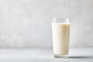 minimalist photograph featuring glass of fresh milk on left side of clean light gray background