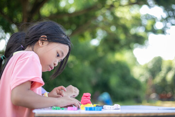 A young girl is sitting at a table with a pile of play dough in front of her