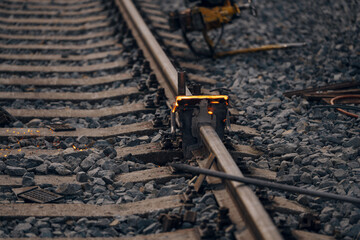 A worker in the process of a railroad track weld repair, reconstruction with a freight train passing