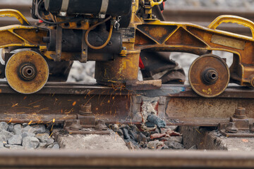 A worker in the process of a railroad track weld repair, reconstruction with a freight train passing
