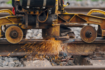 A worker in the process of a railroad track weld repair, reconstruction with a freight train passing