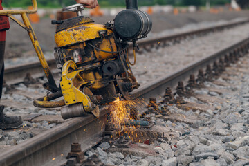 A worker in the process of a railroad track weld repair, reconstruction with a freight train passing