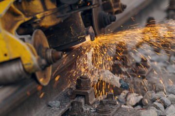 A worker in the process of a railroad track weld repair, reconstruction with a freight train passing