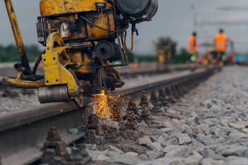 A worker in the process of a railroad track weld repair, reconstruction with a freight train passing