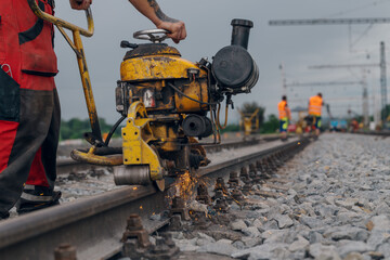 A worker in the process of a railroad track weld repair, reconstruction with a freight train passing