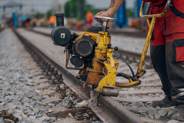 A worker in the process of a railroad track weld repair, reconstruction with a freight train passing
