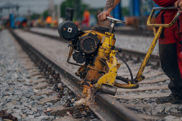 A worker in the process of a railroad track weld repair, reconstruction with a freight train passing