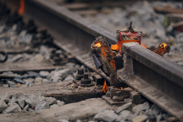 A worker in the process of a railroad track weld repair, reconstruction with a freight train passing