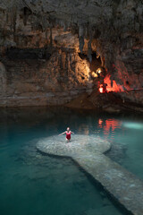 Woman standing on ancient mayan platform enjoying turquoise waters of cenote suytun, a magical place in yucatan, mexico