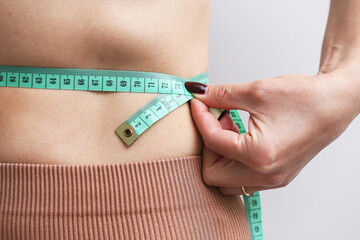 Woman measuring waistline. Fitness and health routine. Slim body and tape measure. Concept of weight loss and shape control. Healthy lifestyle and diet. Body goals and belly measurement.